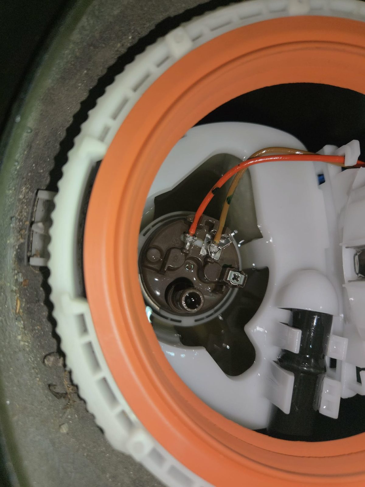 In-tank fuel pump module viewed through the tank access port, showing the pump assembly and wiring where an improperly sealed O-ring let fuel spray back into the tank
