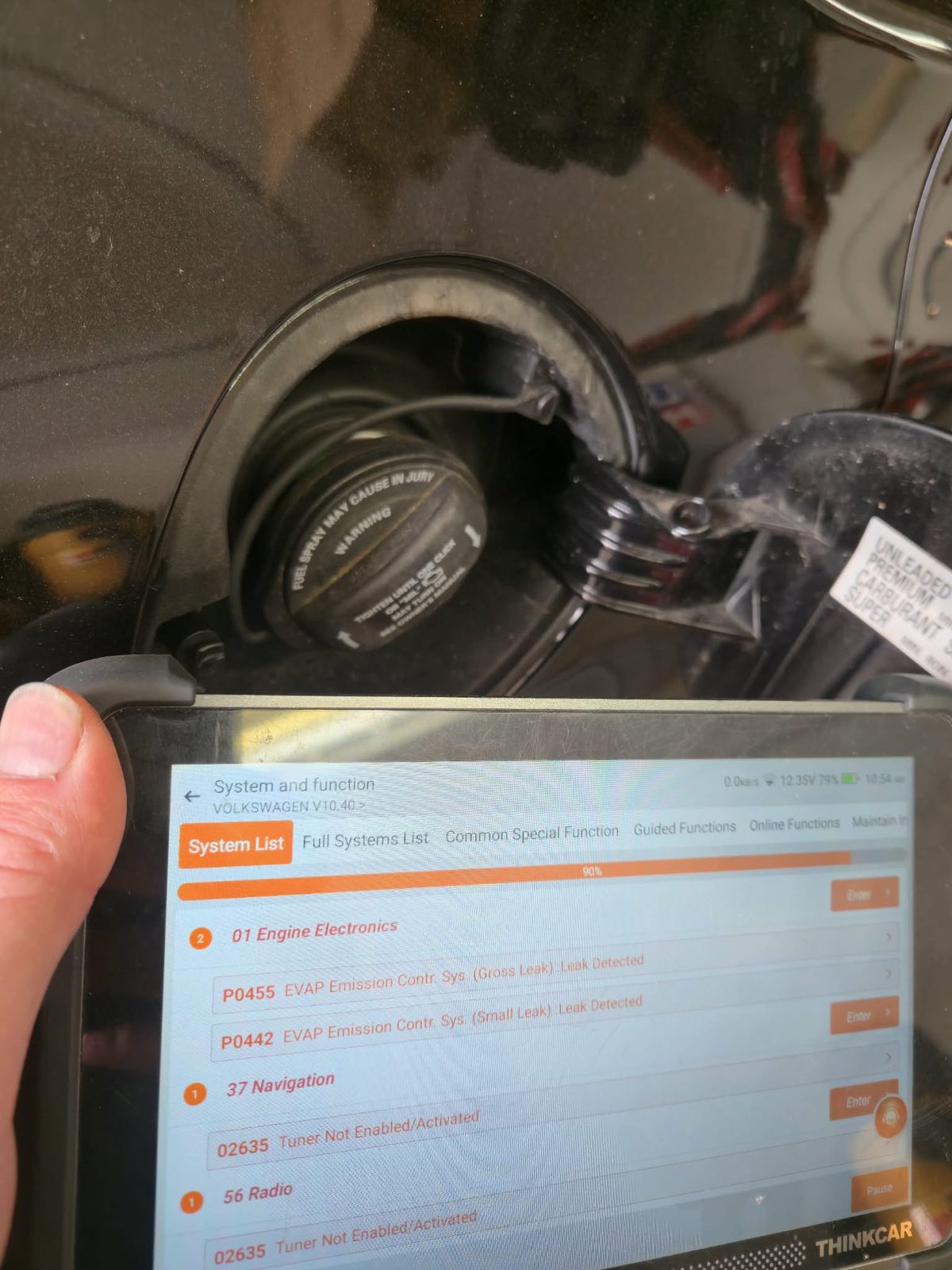 Scan tool showing EVAP trouble codes P0455 and P0442 stored in a vehicle's engine electronics module, held next to the open fuel filler door