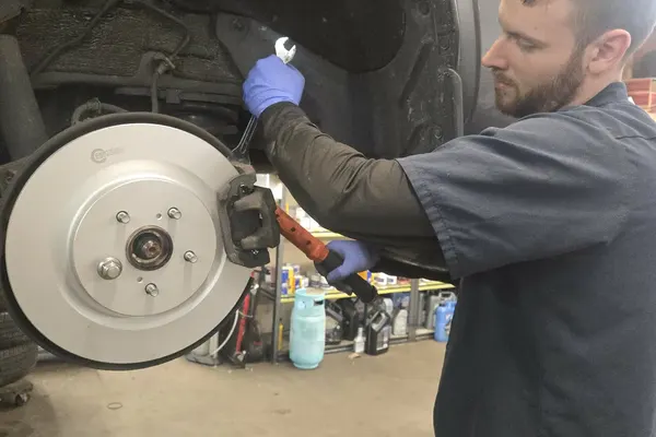 Mechanic installing a new brake rotor and caliper in Port Coquitlam