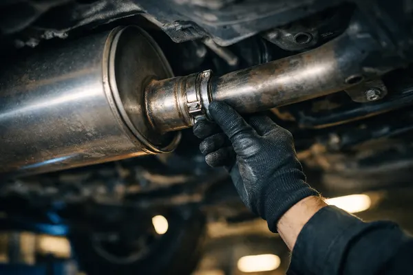 Muffler and exhaust pipe being inspected under a car on a hoist